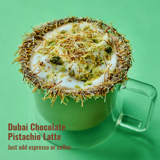 Dubai Chocolate Latte with kataifi and chocolate rim with pistachio pieces for granish in clear mug and green background