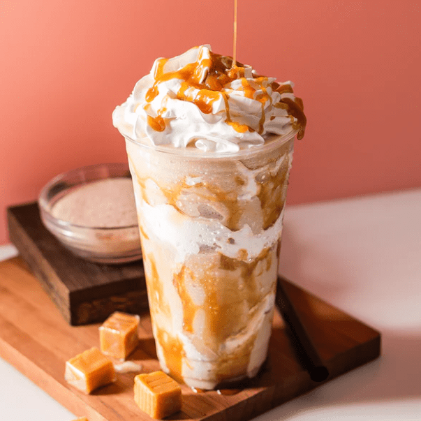 Caramel Frappe with whipped cream and caramel drizzle and chuncks of caramel next to it