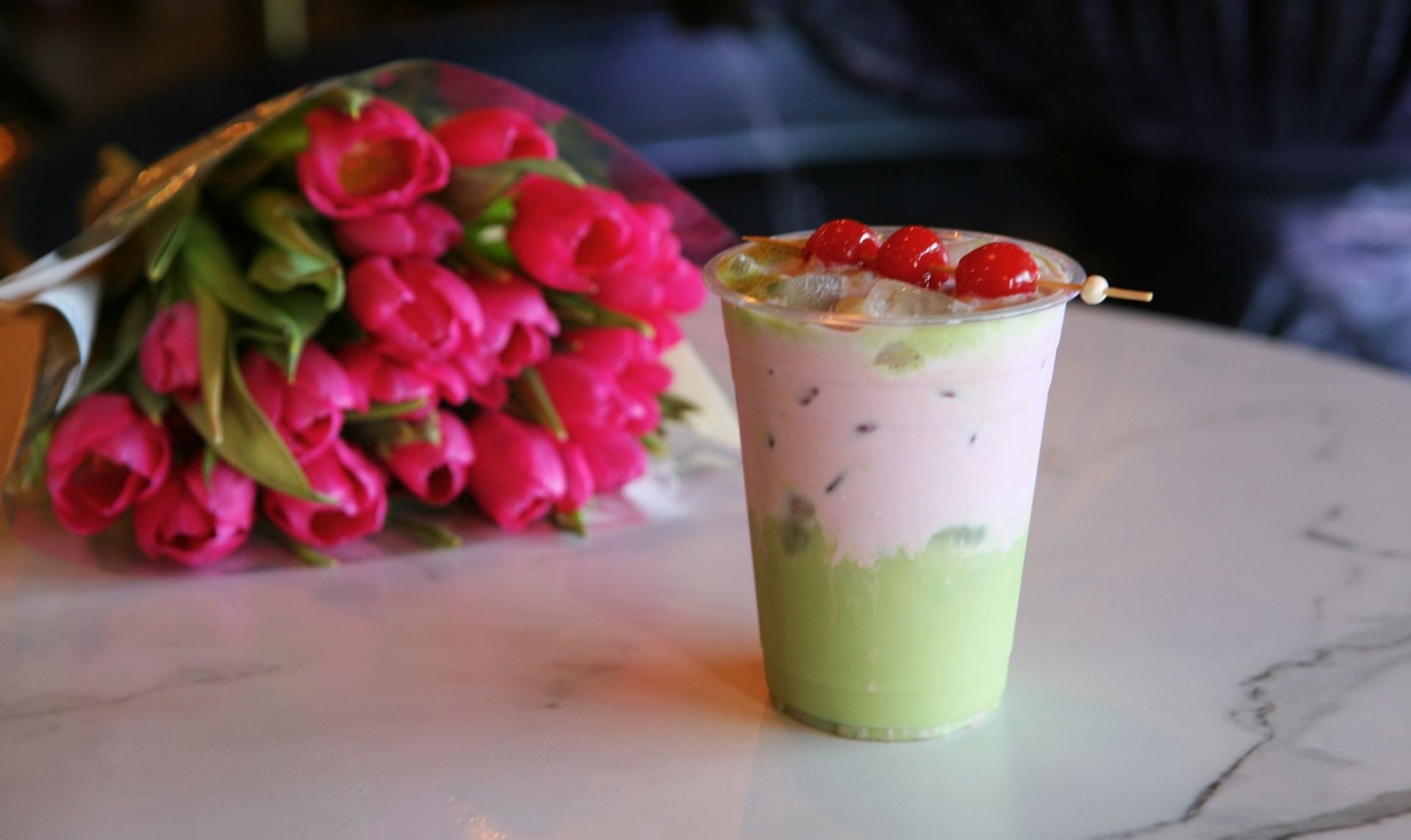 Spring layered Drink with cherries on top on table by pink tullips